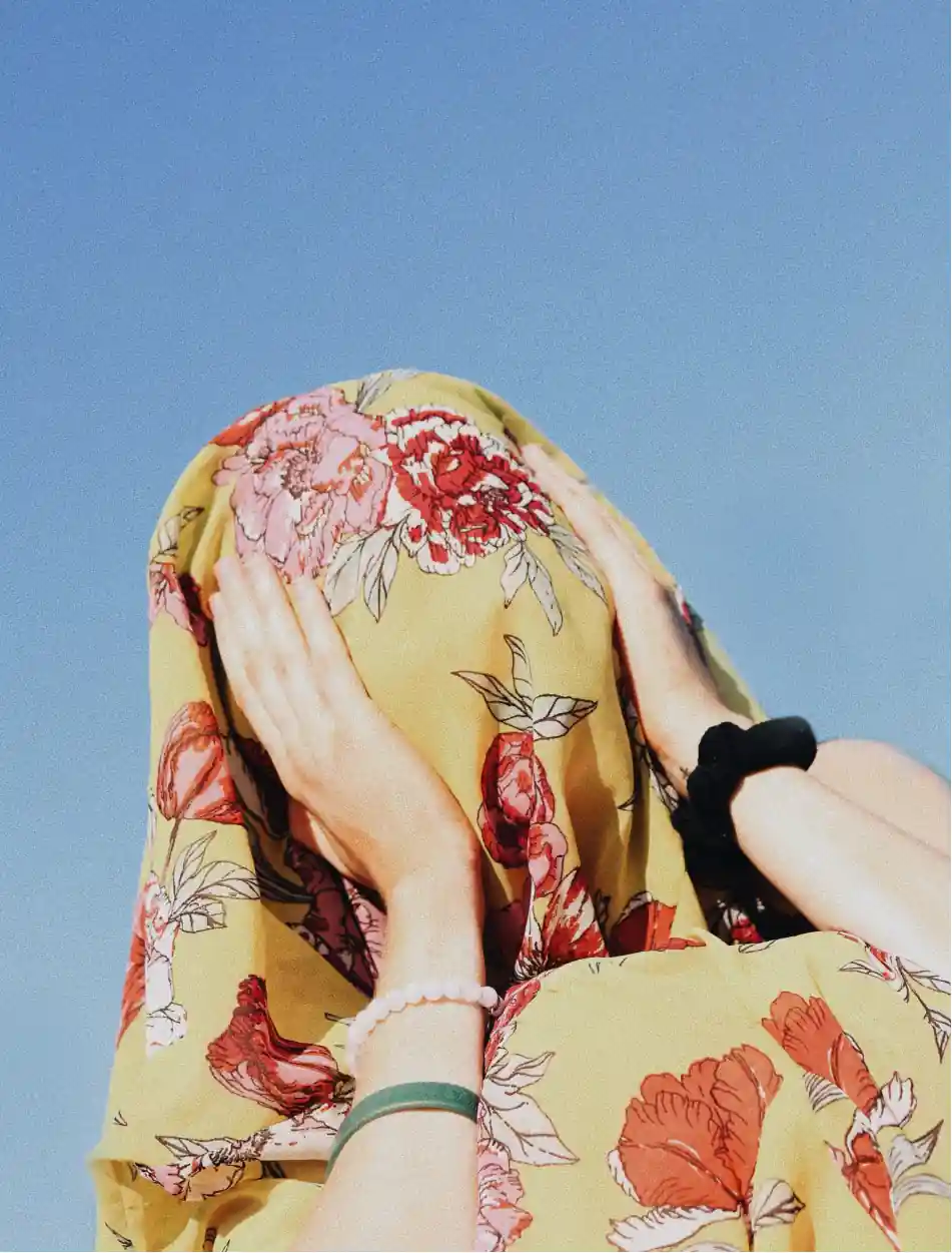 Portrait of a person with a sheet on their face, with their hand against their face